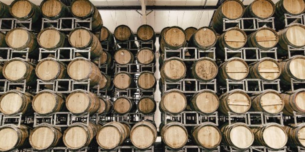 Stacks of oak wine barrels in Coopers Creek’s barrel room, a must-visit stop on Auckland self-drive winery tasting tours.