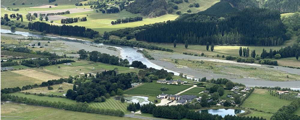 Aerial view of Hawke’s Bay vineyards, river, and rolling green hills in New Zealand, perfect for a scenic road trip between Auckland and Wellington