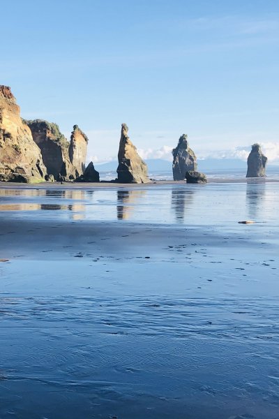 Three Sisters rock formations with dramatic cliffs and black sand beach near New Plymouth, a scenic coastal highlight on the Auckland to Wellington road trip via Taranaki.