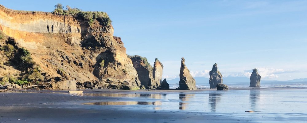Three Sisters rock formations with dramatic cliffs and black sand beach near New Plymouth, a scenic coastal highlight on the Auckland to Wellington road trip via Taranaki.