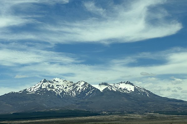 Panoramic view of Mount Ruapehu’s snow-capped volcanic peaks under blue sky in Tongariro National Park, a highlight of the Auckland to Wellington drive