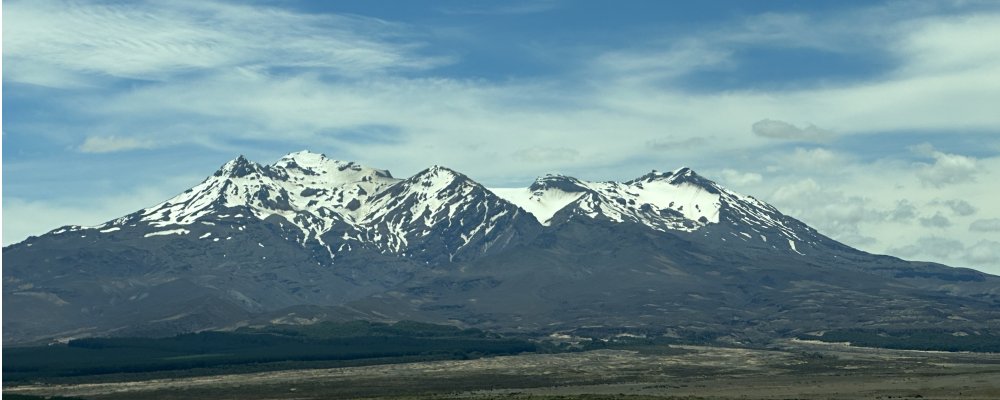 Panoramic view of Mount Ruapehu’s snow-capped volcanic peaks under blue sky in Tongariro National Park, a highlight of the Auckland to Wellington drive
