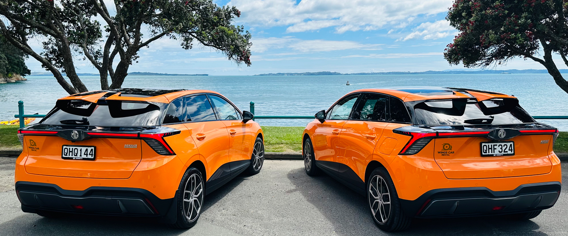 wings-car-rental-auckland-home-page-cover-image-two-orange-electric-cars-near-beach